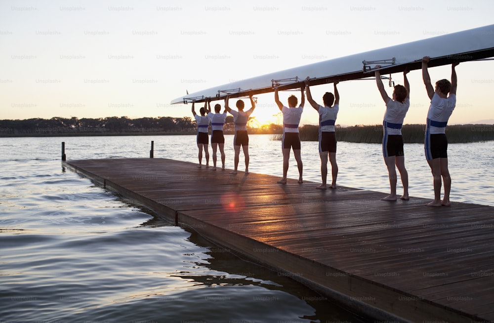 a group of people standing on a dock holding a surfboard