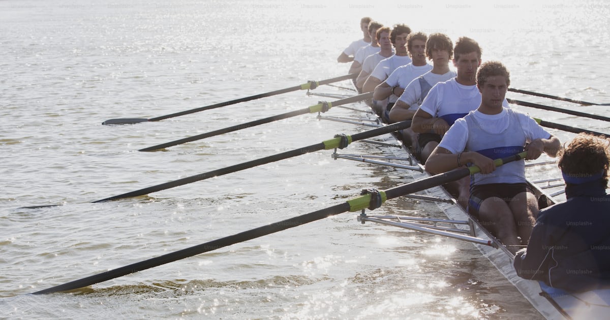 A row of rowers sitting on the side of a boat photo – Rowing Image on ...