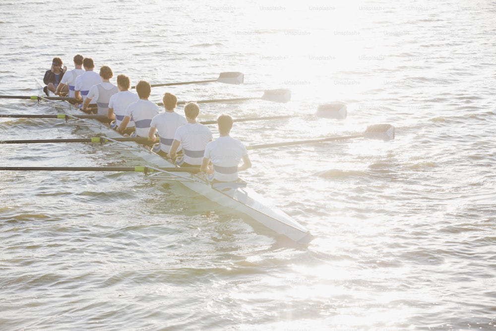 Eine Reihe von Ruderern in weißen Hemden rudert über das Wasser