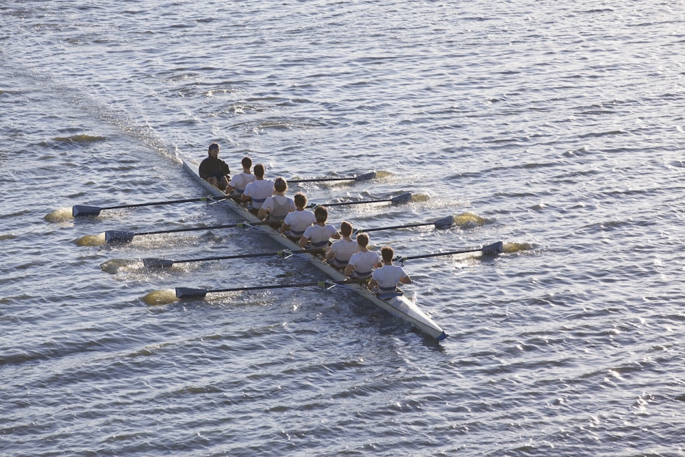 Un gruppo di persone che remano una barca su uno specchio d'acqua