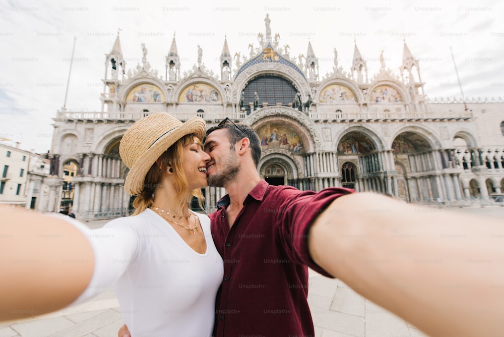 Giovane coppia di amanti che scatta un ritratto selfie in Piazza San Marco a Venezia, Italia. Le persone che si amano si baciano all'aperto. Filtro vintage