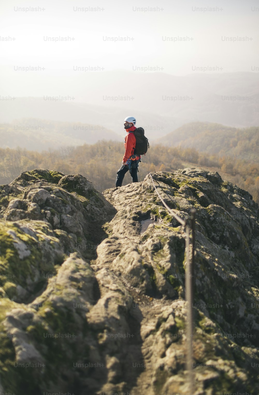 Voll ausgestatteter Bergsteiger mit Rucksack steht auf dem felsigen Aussichtspunkt.