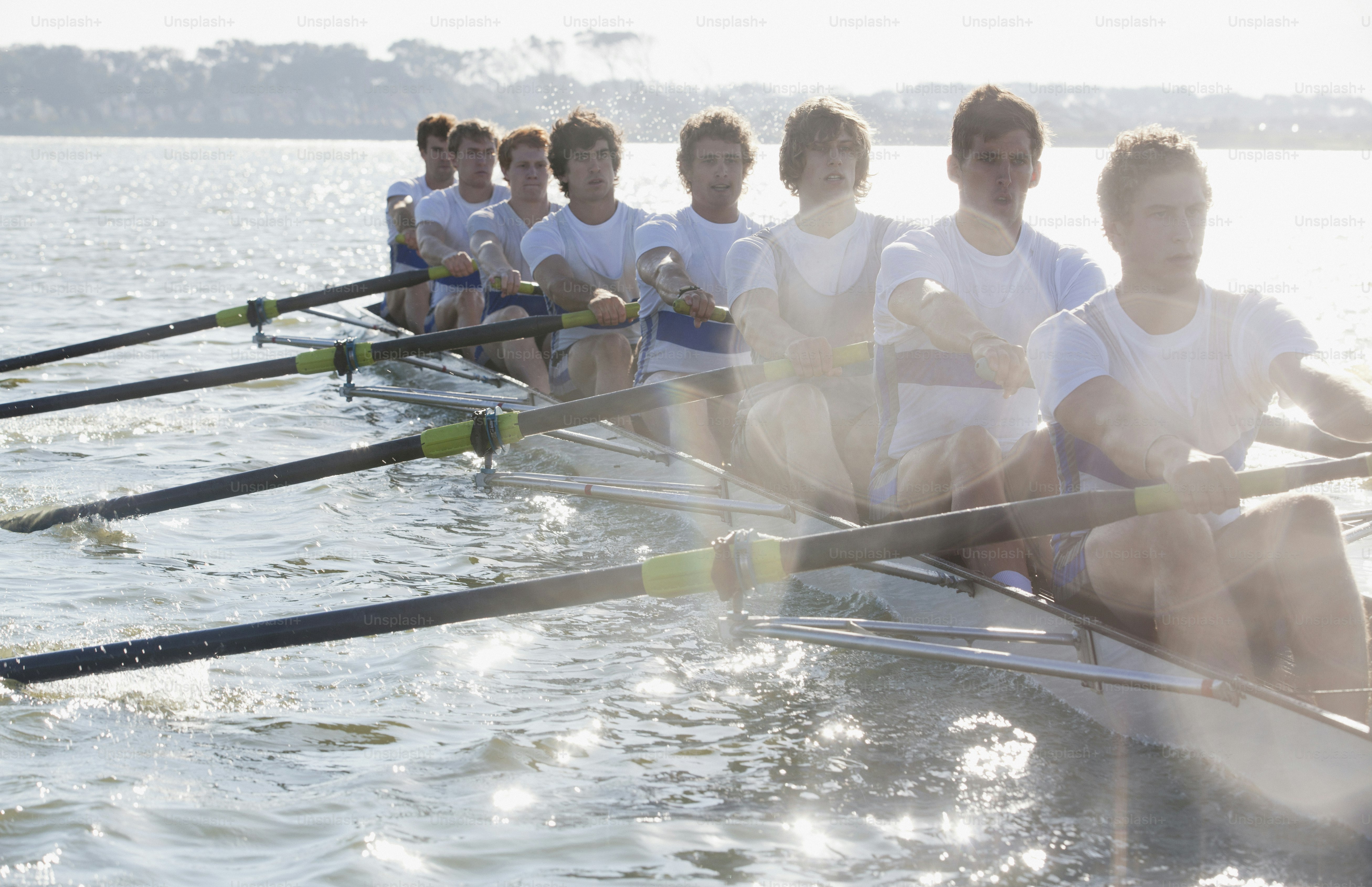 A group of men sitting on top of a boat in the water photo – Rowing ...