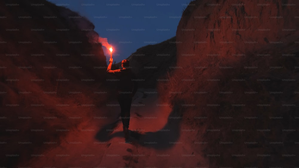 El hombre con un palo de fuego caminando por las montañas
