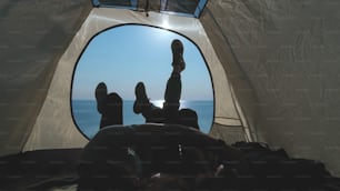 O homem e a mulher deitados na tenda do acampamento perto do mar