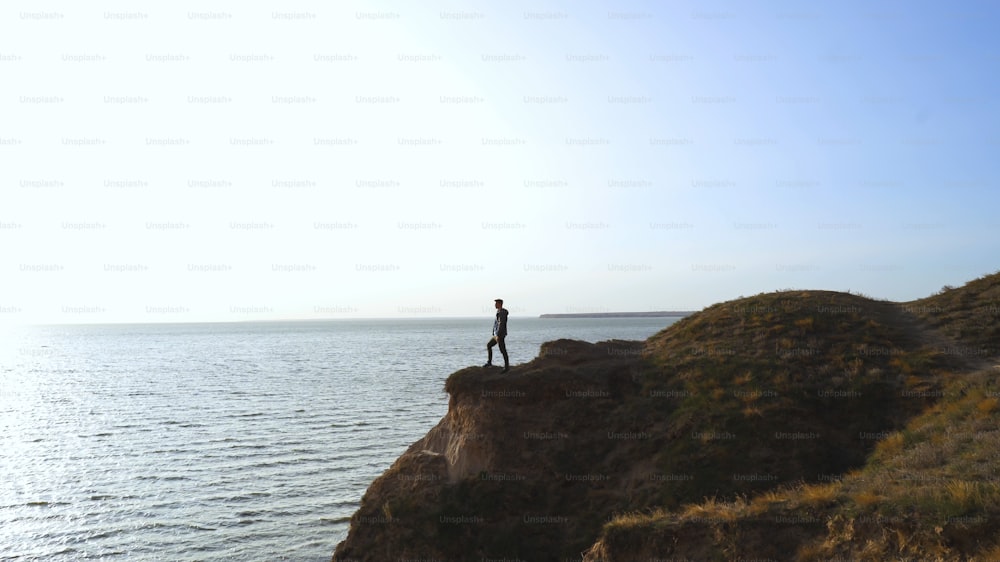 The man stands on the mountain edge on the seascape background