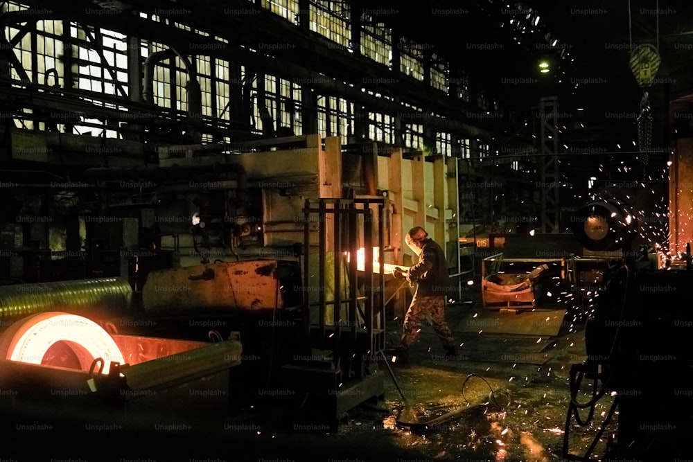 Persone che saldano il metallo durante il lavoro nell'impianto di lavorazione dei metalli