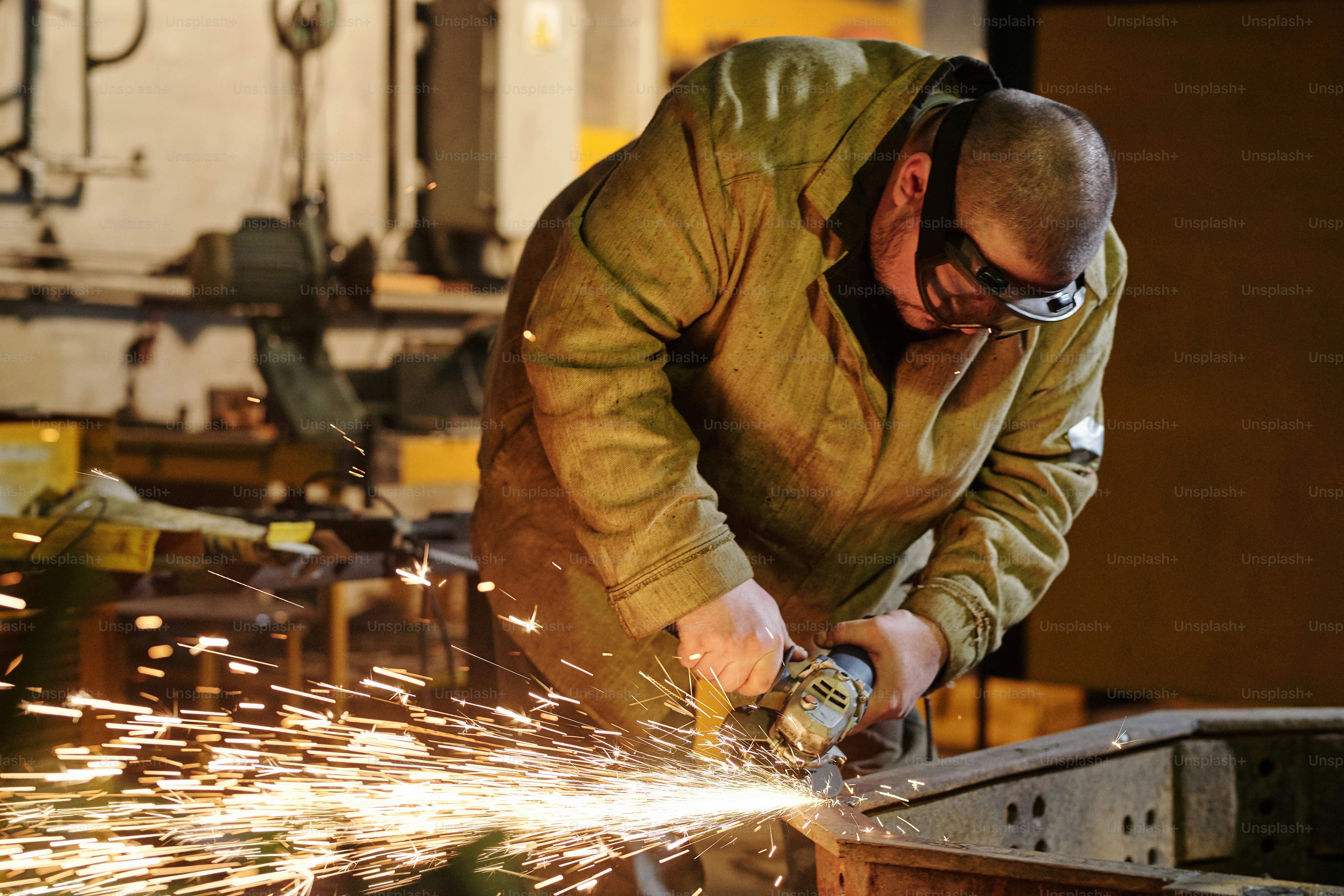 Worker with protective mask welding metal and sparks in the factory