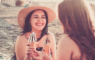 Friends women people have fun together in friendship and love eating and enjoying an ice cream at the beach - summer holiday vacation people have fun and smile - beautiful curvy healthy females