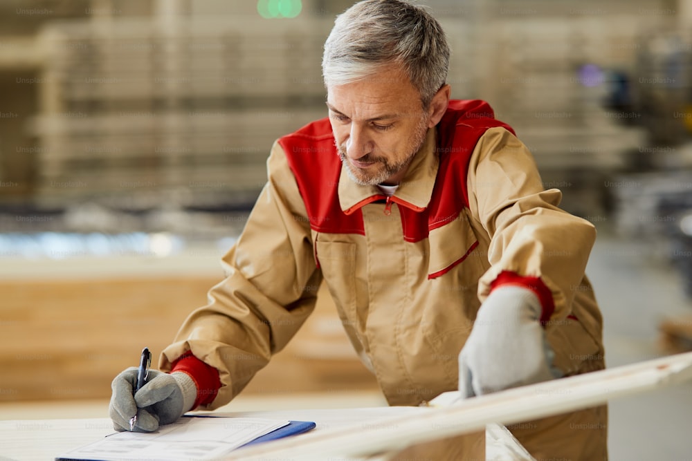 Carpinteiro verificando medidas enquanto trabalhava em um novo projeto na oficina de carpintaria.
