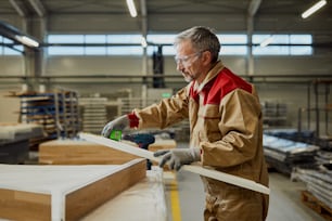 Woodworker checking measurements of a plank while working at carpentry workshop.