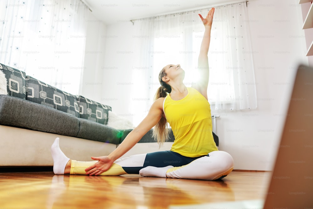 Fit muscular sportswoman sitting on the floor and doing fitness exercises.