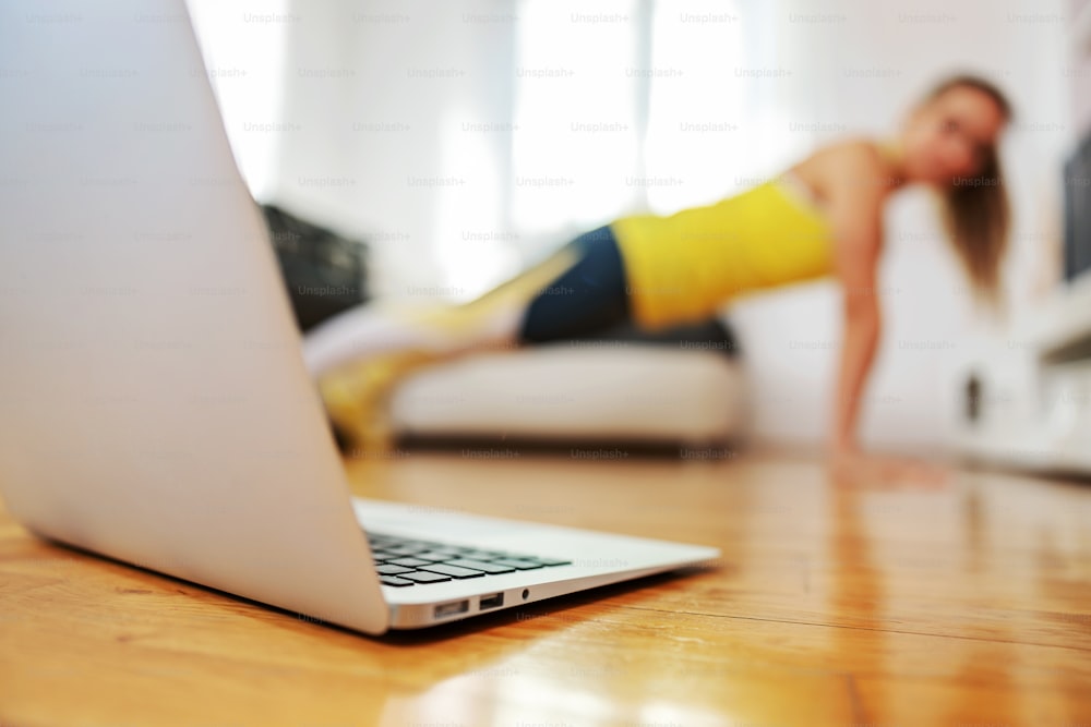 Instrutora de fitness fazendo flexões em casa e tendo aula online com seus alunos.