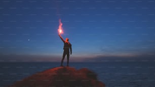 The man with a fire stick standing on the mountain top near the sea