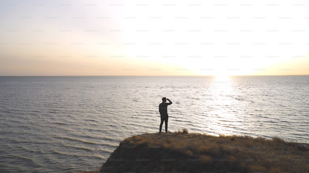 O homem de pé na costa rochosa do mar