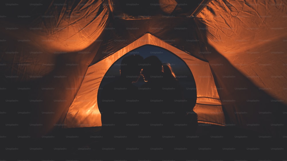 O jovem casal sentado no acampamento noturno