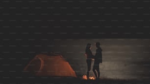 La pareja romántica de pie en abrazos en la orilla del mar nocturno