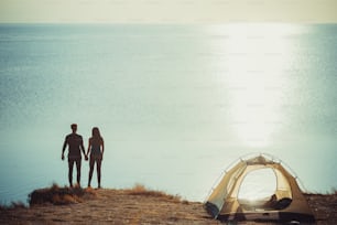 O homem e a mulher descansam no acampamento perto do mar