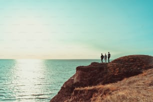 As três pessoas em pé no topo da montanha perto do mar