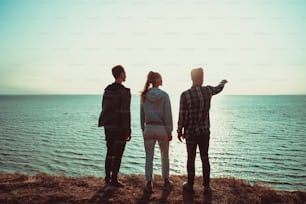 The three people standing on the mountain top near the sea