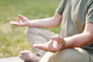 Close-up of senior man sitting in lotus position and doing yoga