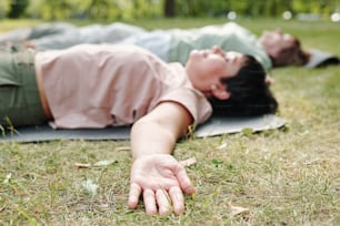 Close-up of people lying on green grass and relaxing with their eyes closed outdoors