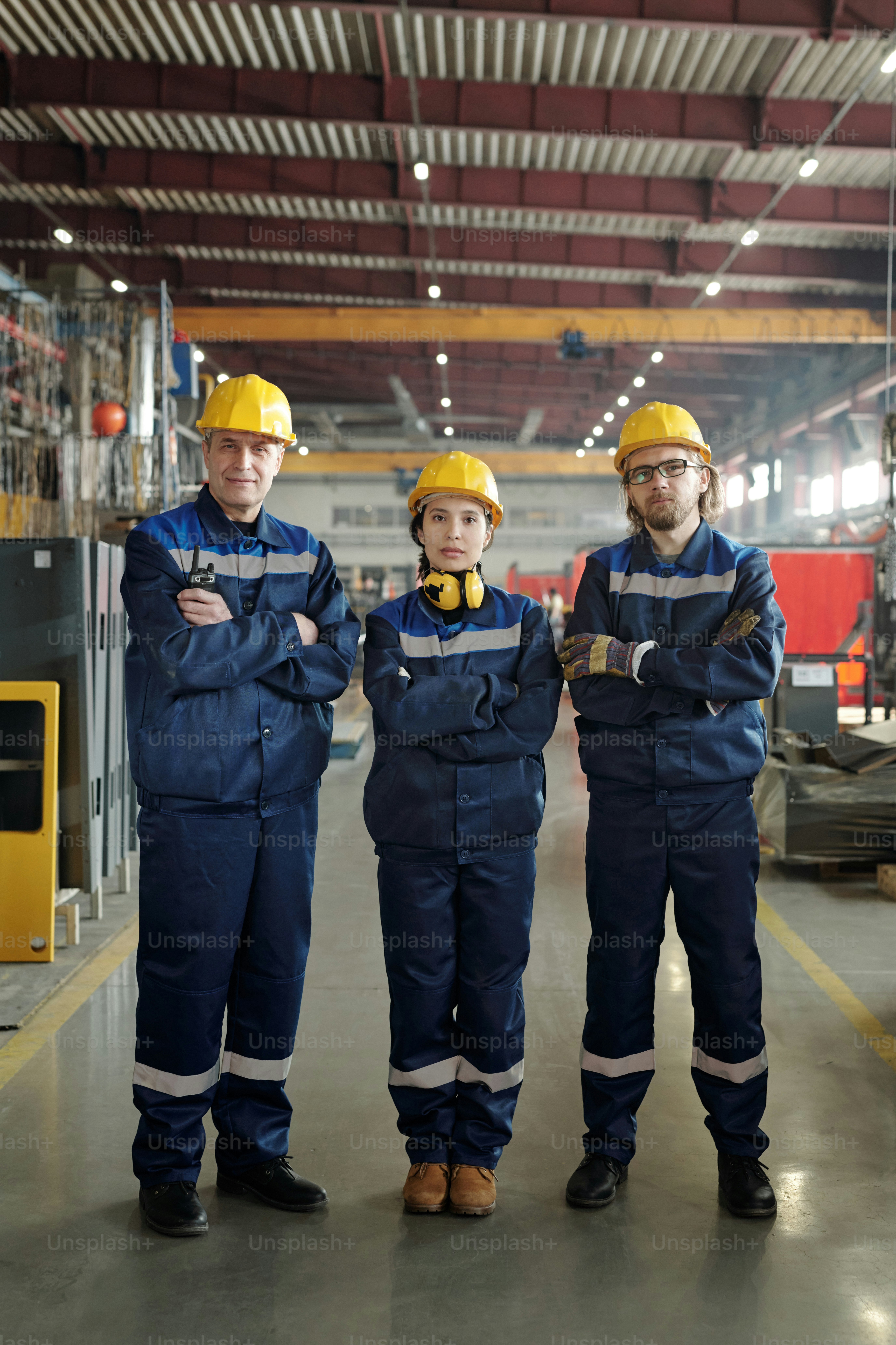 Reihe zeitgenössischer Arbeiter und Arbeiterinnen großer Industriebetriebe oder Fabriken, die vor der Kamera stehen und Sie in der Werkstatt ansehen