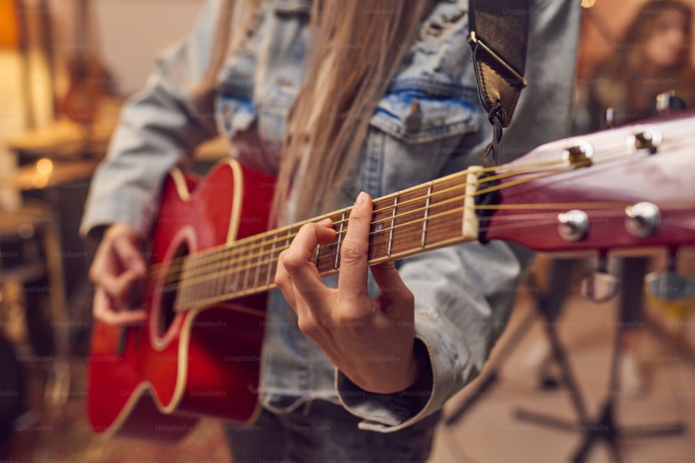 Close-up of woman learning to play electric guitar during musical lesson in studio