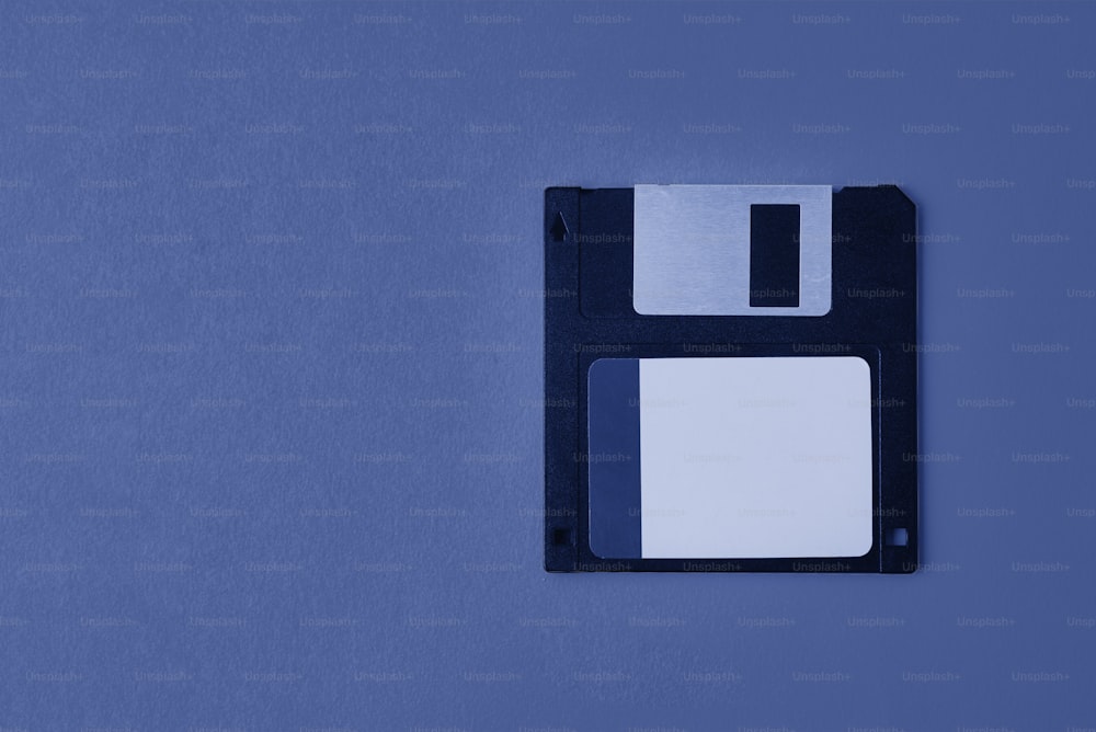 Dischetto floppy nero su sfondo blu. Dischetto del computer dell'annata, primo piano
