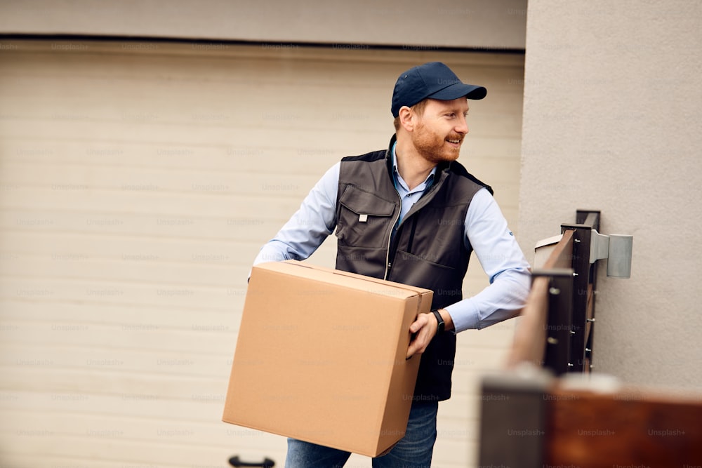 Smiling courier carrying package and delivering online order to customer at home address.