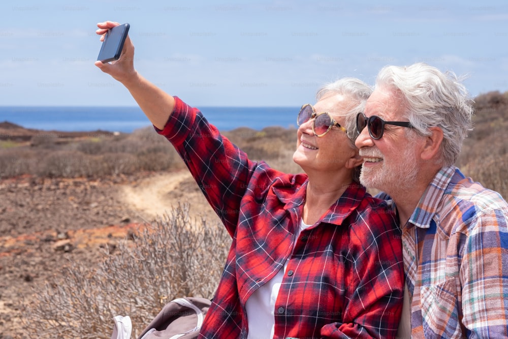 Beautiful couple of travelers enjoying outdoors excursion taking a selfie. Horizon over sea and sunny day
