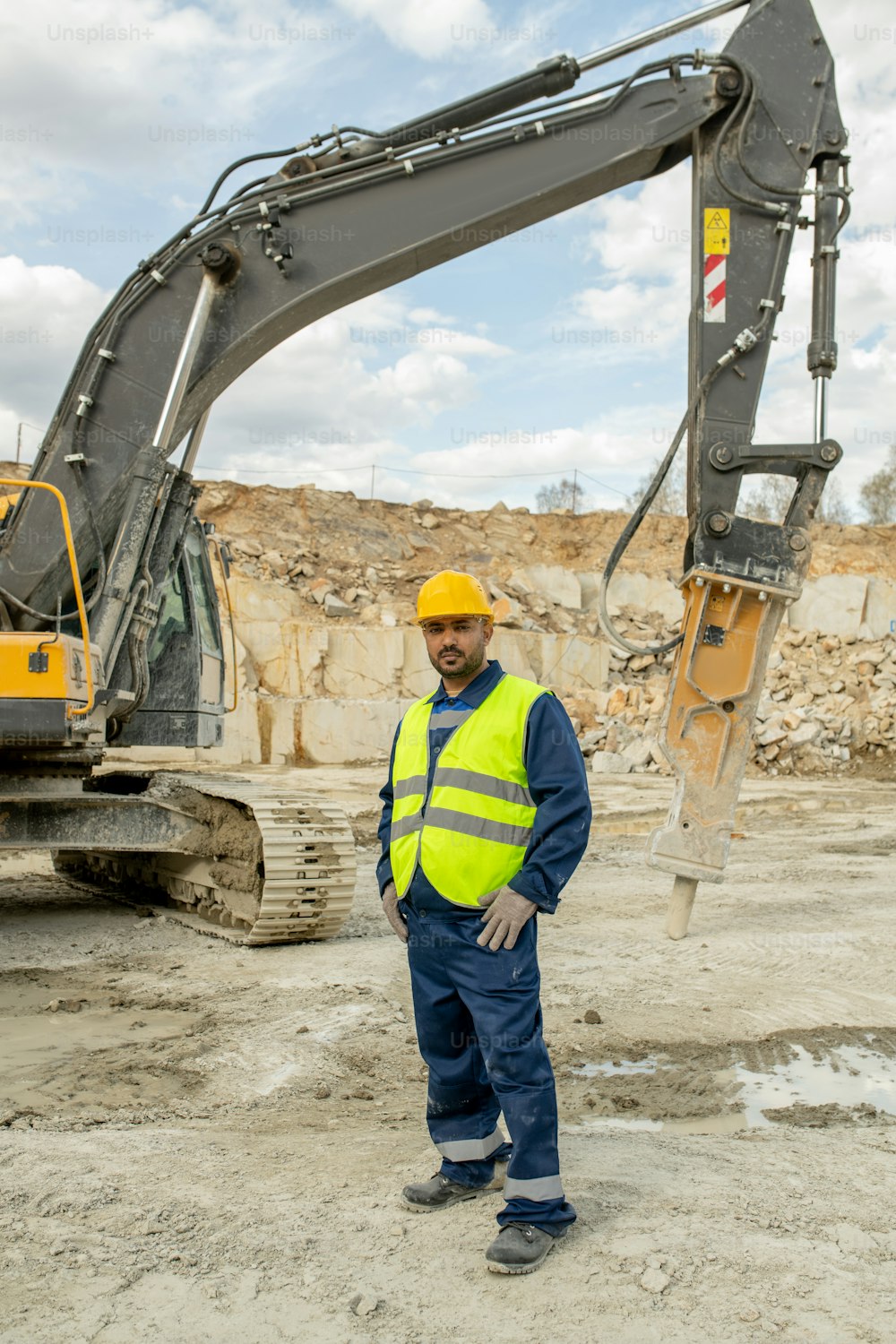 Engineer or builder in uniform standing against bulldozer on construction site