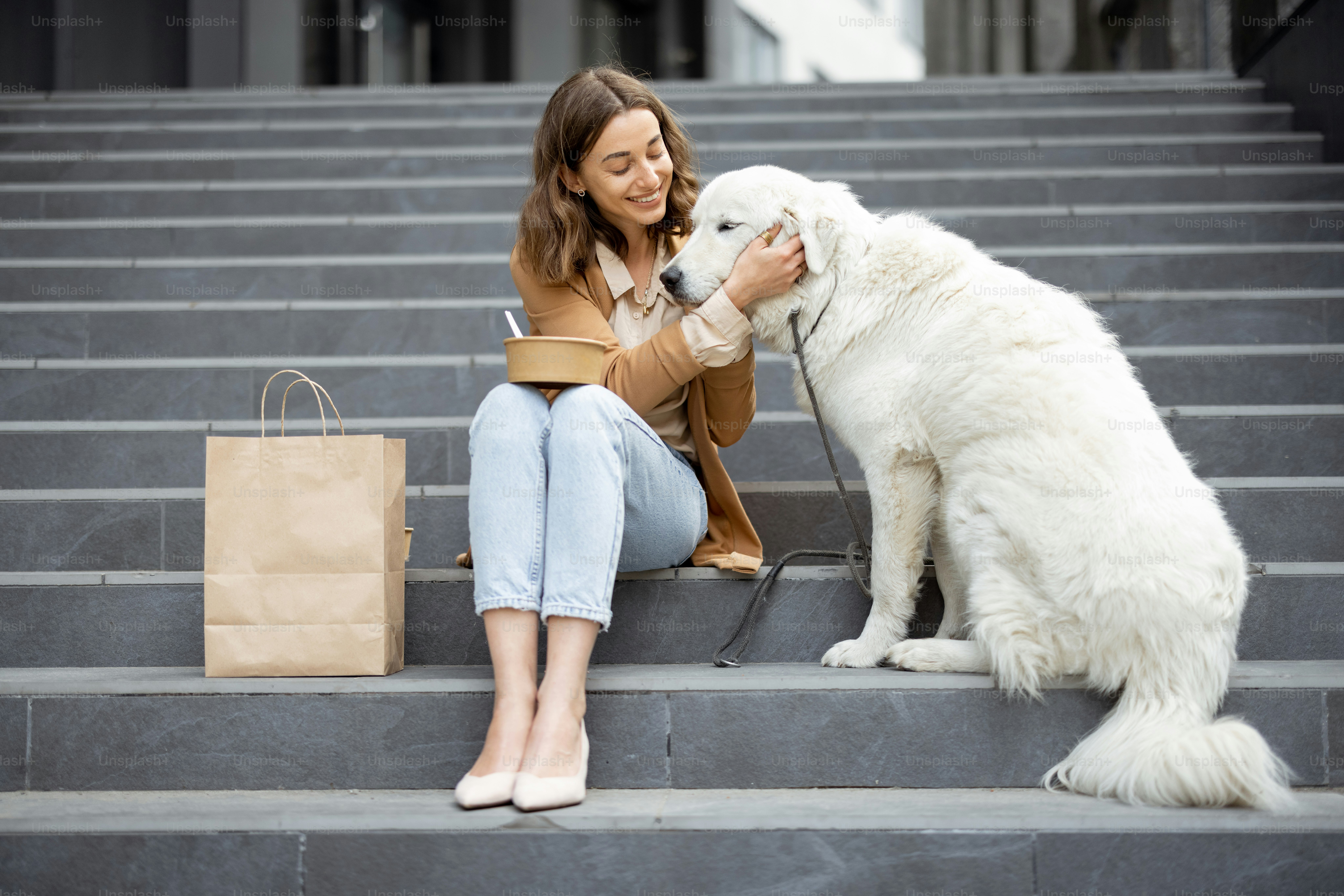A woman petting a large white dog while sitting on grey stone steps