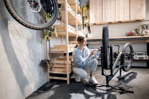 Joven manitas bombeando ruedas de bicicleta en el pequeño y hermoso taller de su casa. Concepto de reparación y bricolaje de bicicletas