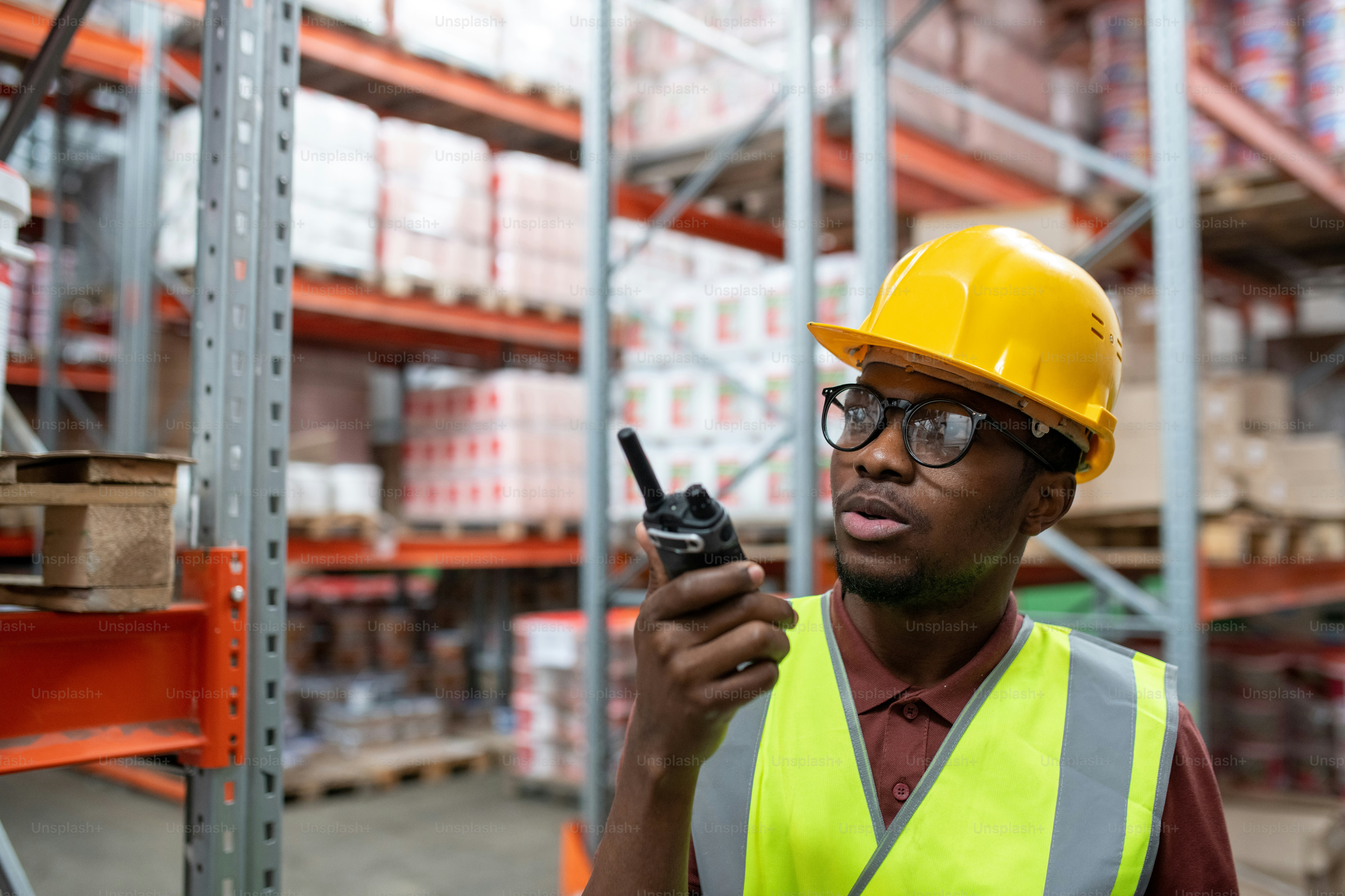 Serious young African-American storeroom manager in yellow hardhat and ...