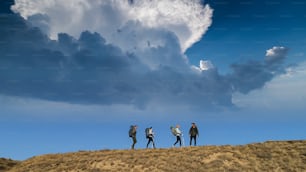 Los cuatro viajeros están de pie en la cima de la montaña contra el hermoso cielo