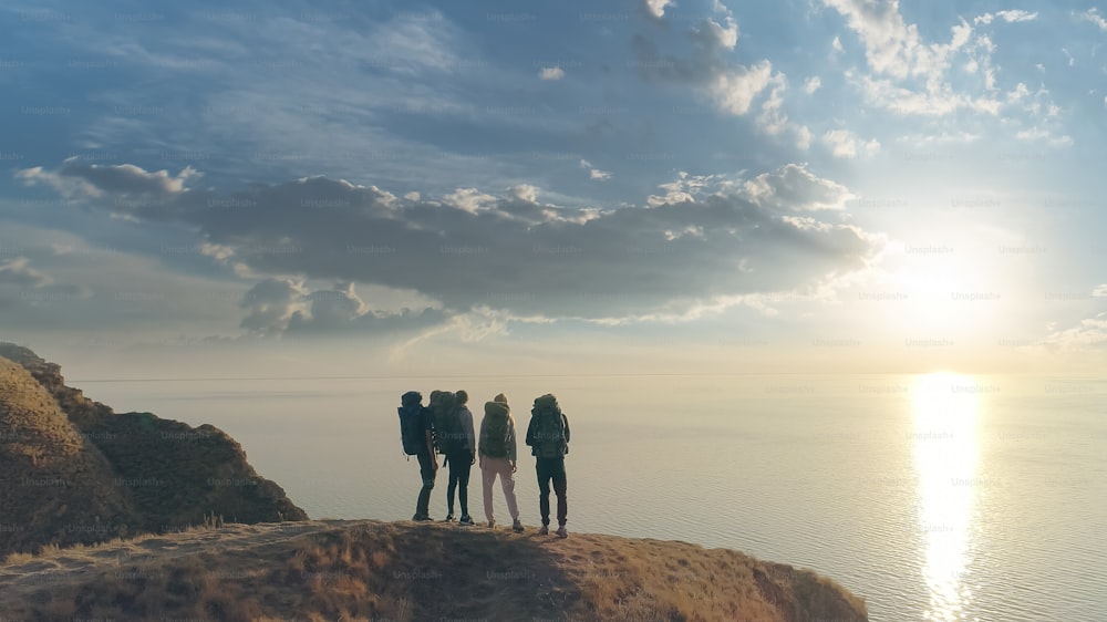 海の景色を背景に山頂に立つ4人