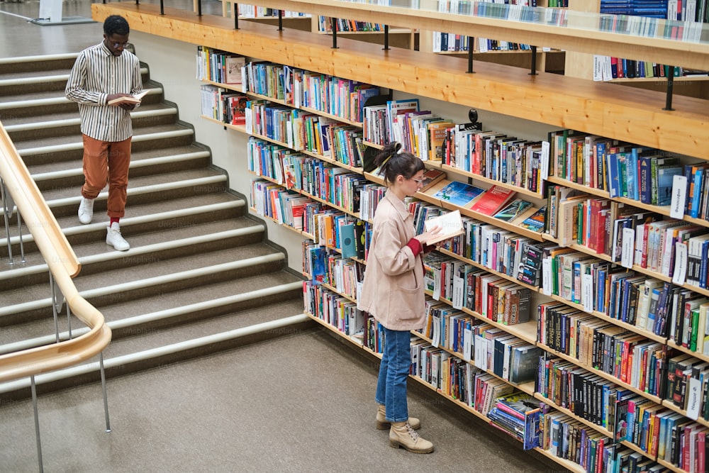 Giovani che scelgono i libri e li leggono in biblioteca