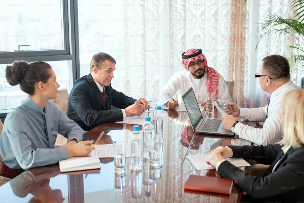 A group of delegates or businesspeople sitting around a table during meeting
