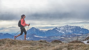 Una chica de marcha nórdica caminando sola en las montañas