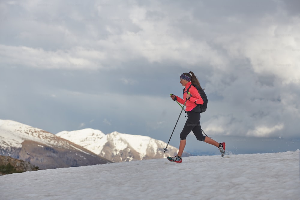 Mujer atleta corre en la nieve para la práctica de skyrunning