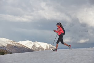 Une athlète féminine court sur la neige pour s’entraîner au skyrunning