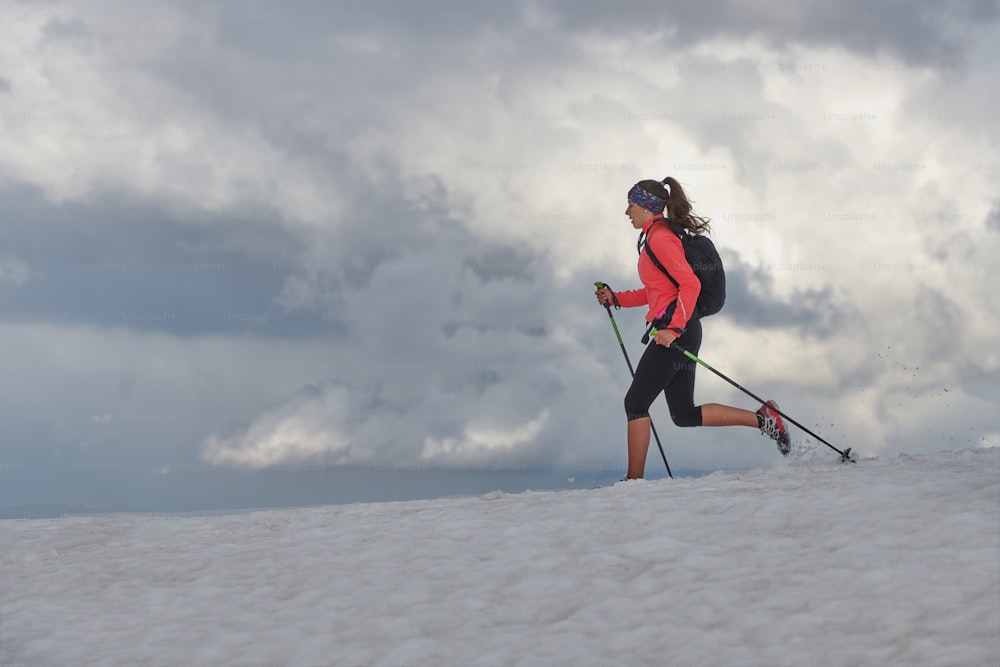 Skyrunning girl practices on snow in the mountains