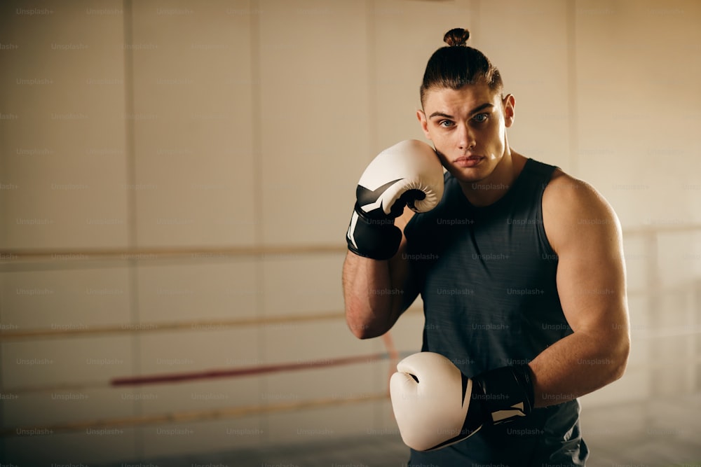 Portrait of young male fighter with boxing glovers during sports training at boxing club.