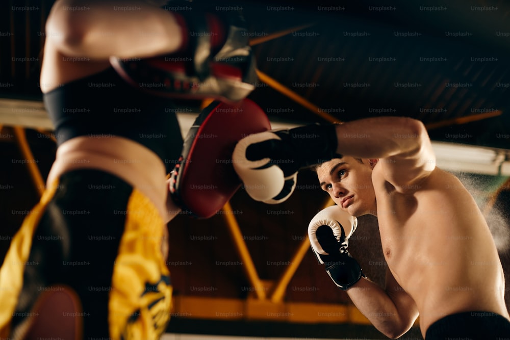 Vue en contre-plongée de boxeurs s’entraînant lors d’un entraînement sportif dans un club de boxe.