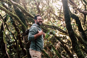 Standing traveler bearded man walk and enjoy the free nature forest in trekking activity - concept of handsome male people explore the woods with backpack and enjoy mountain vacation