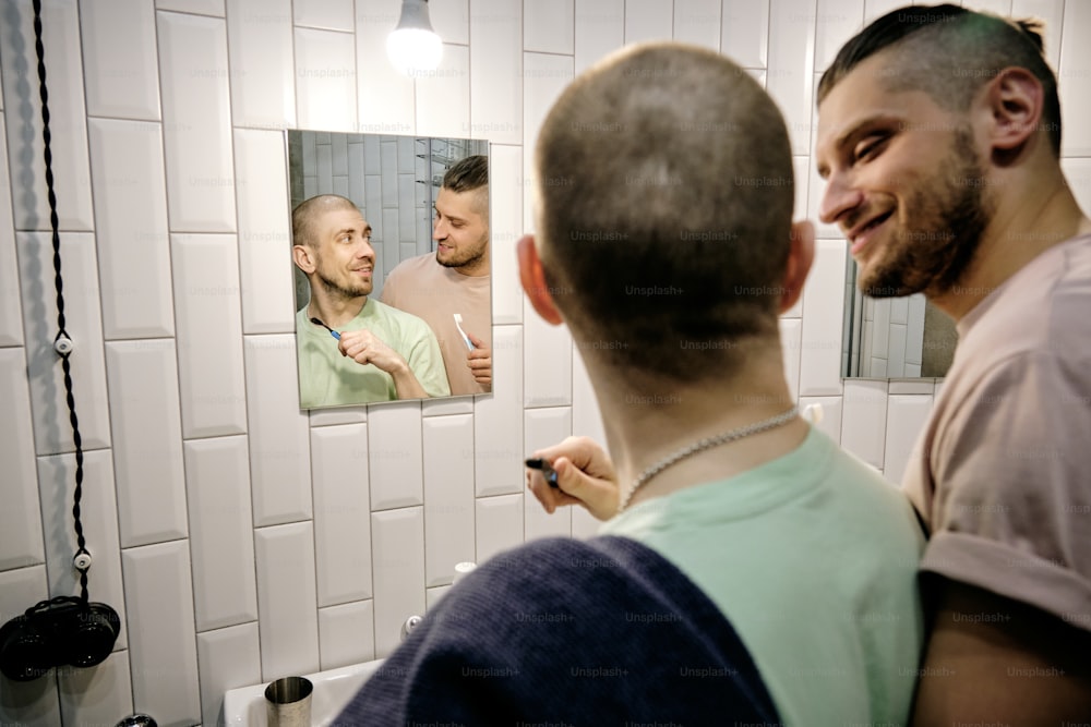 Glücklicher junger schwuler Mann schaut seinen Freund im Badezimmer an