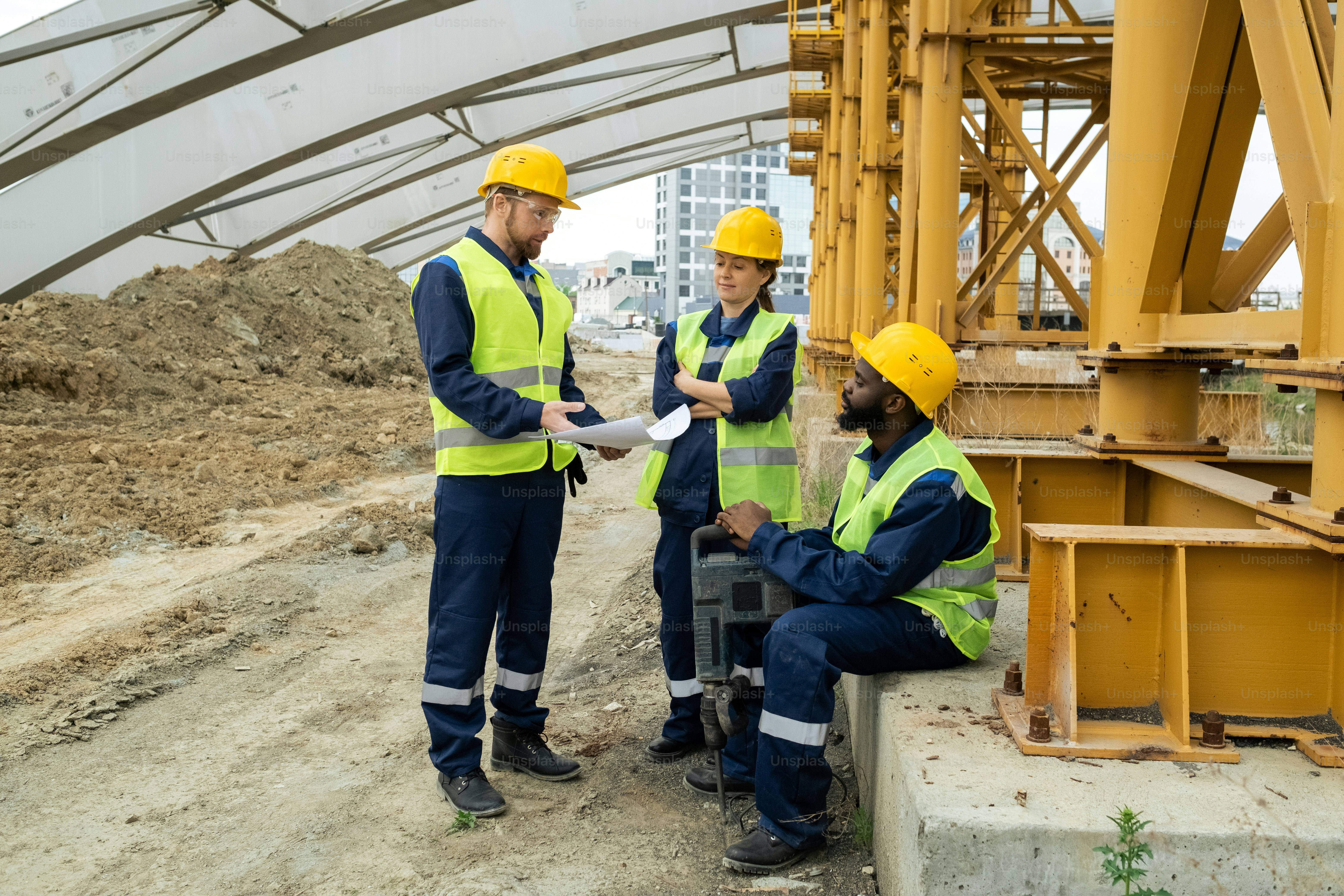 Drei Bauherren diskutieren Bauplan auf Baustelle