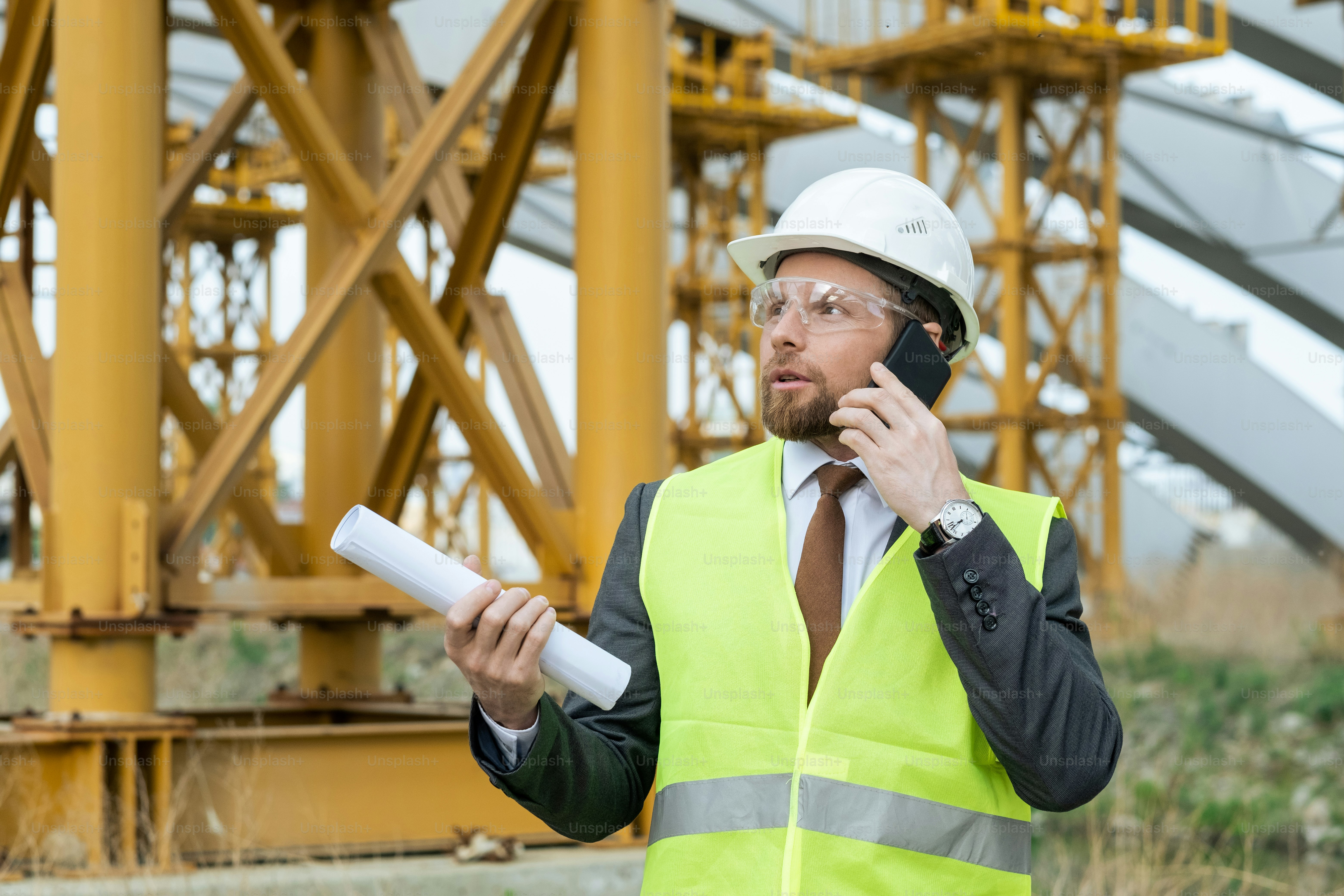 Junge Ingenieurin in Arbeitskleidung telefoniert auf der Baustelle