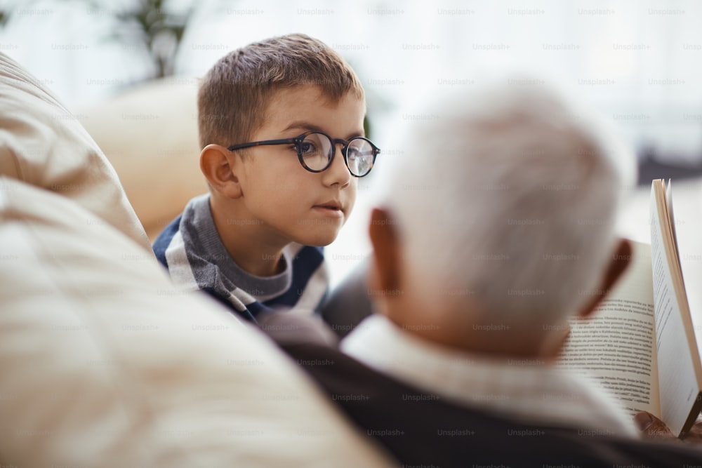 Niño pequeño escuchando a su abuelo mientras se comunica y pasa tiempo juntos en casa.